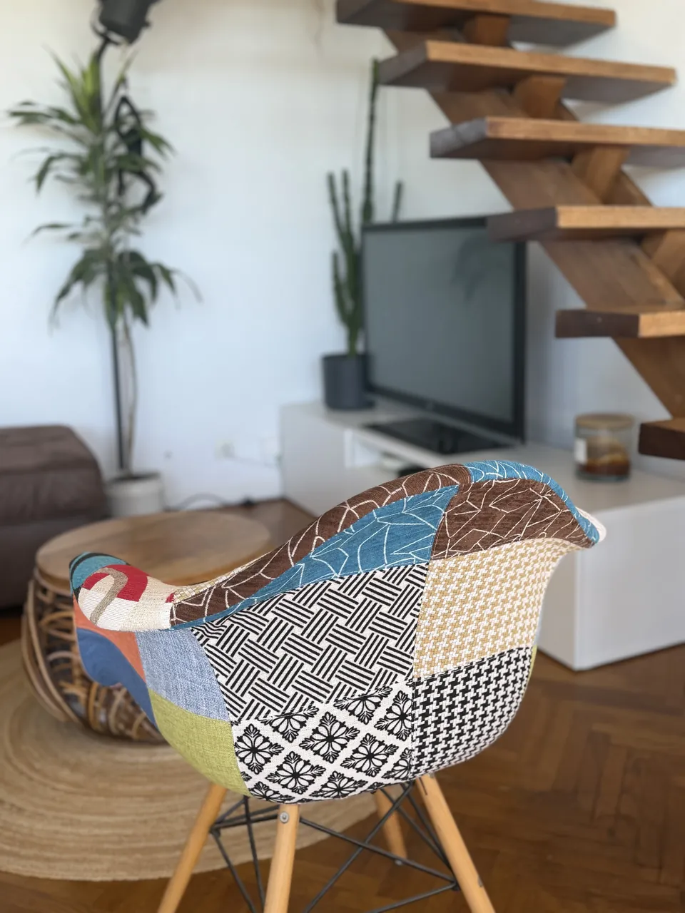 Fauteuil en patchwork bleu et blanc devant l'escalier en bois d'un appartement