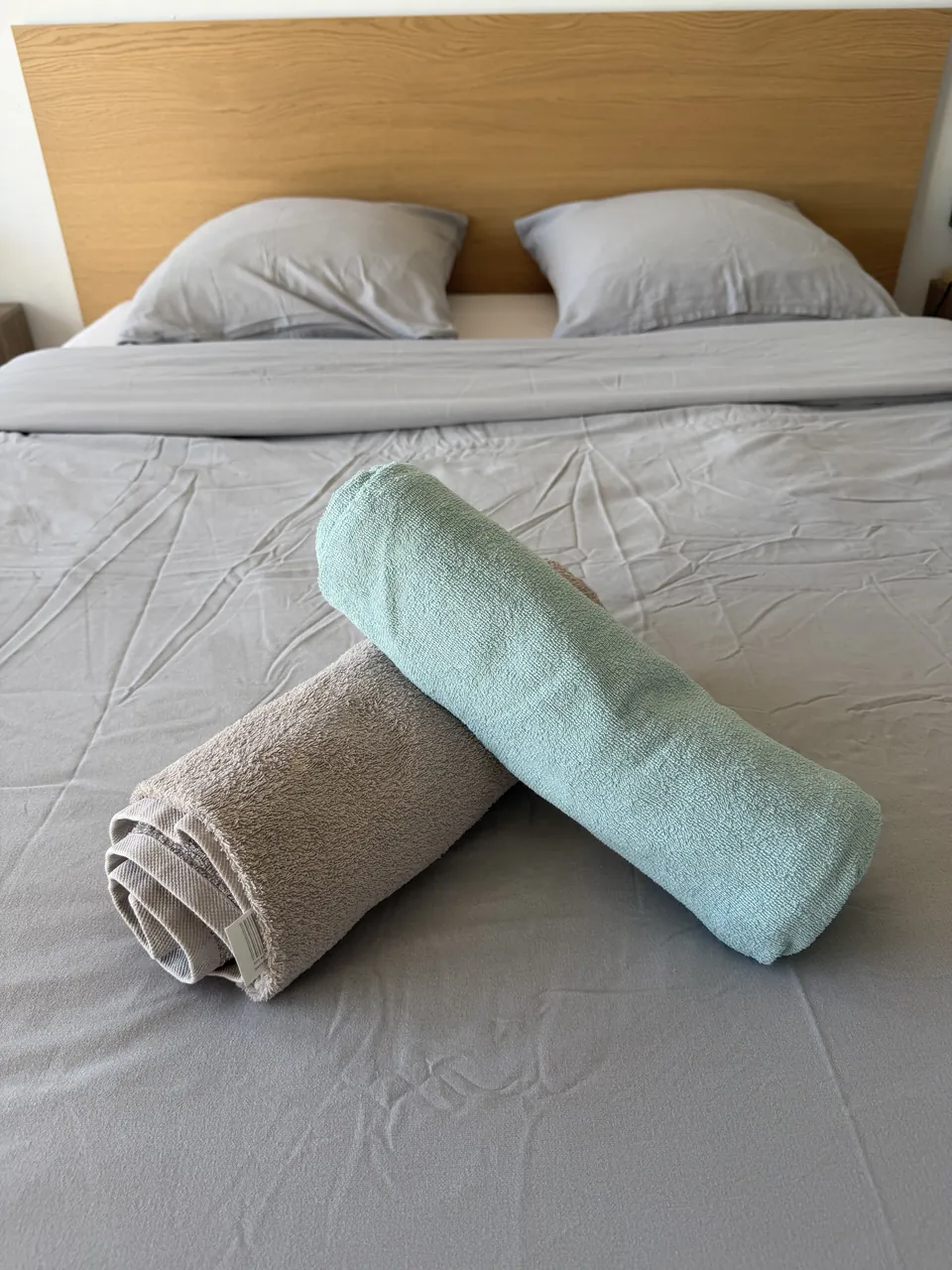 Lit fait avec draps gris et serviettes roulées posées pour l'arrivée des voyageurs