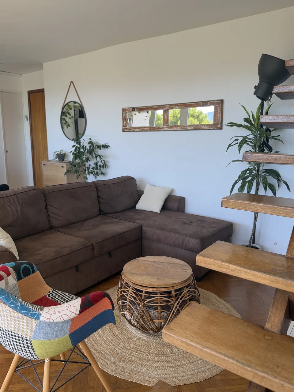 Salon d'un logement préparé pour les voyageurs, canapé, table basse en rotin et fauteuil en patchwork